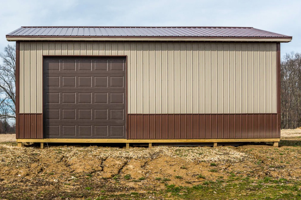 tan and brown trimmed pole barn garage with one brown overhead door