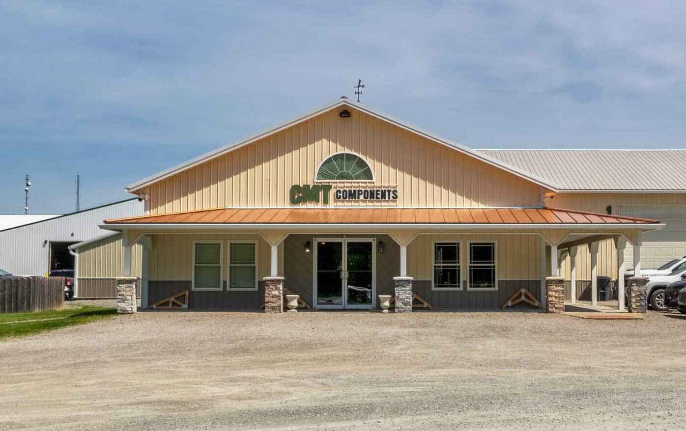 tan building with green CMT logo on front and cars in lot
