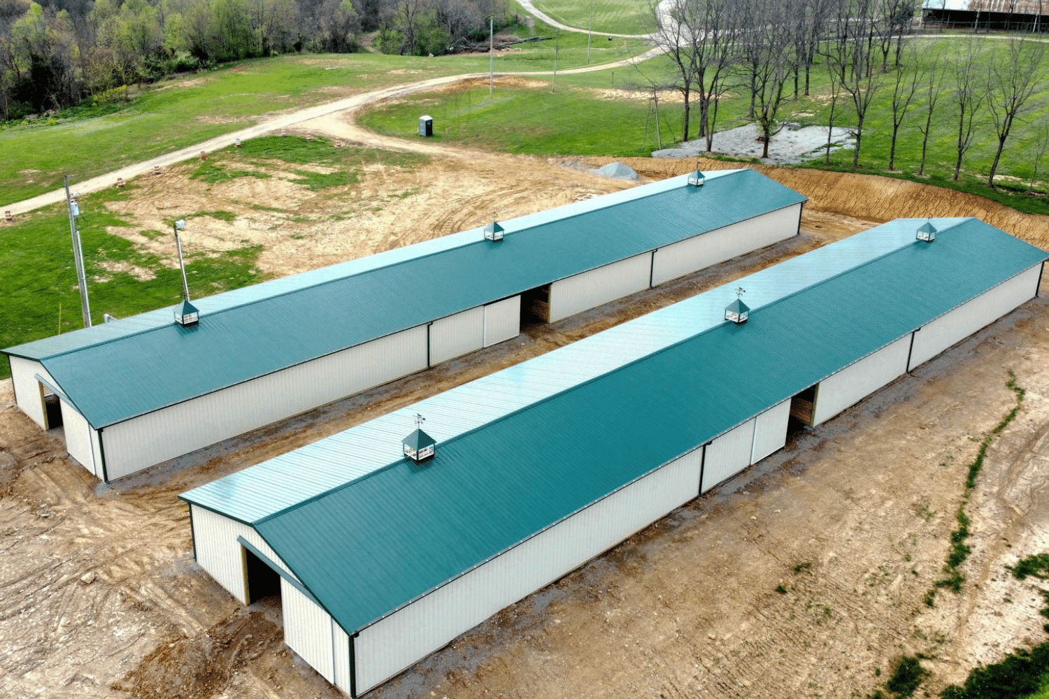 two white 60x100 agricultural pole barn kit with green roof and doors
