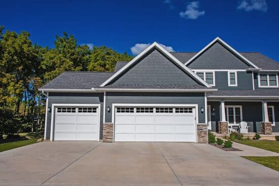 two white garage doors with transom windows on gray home