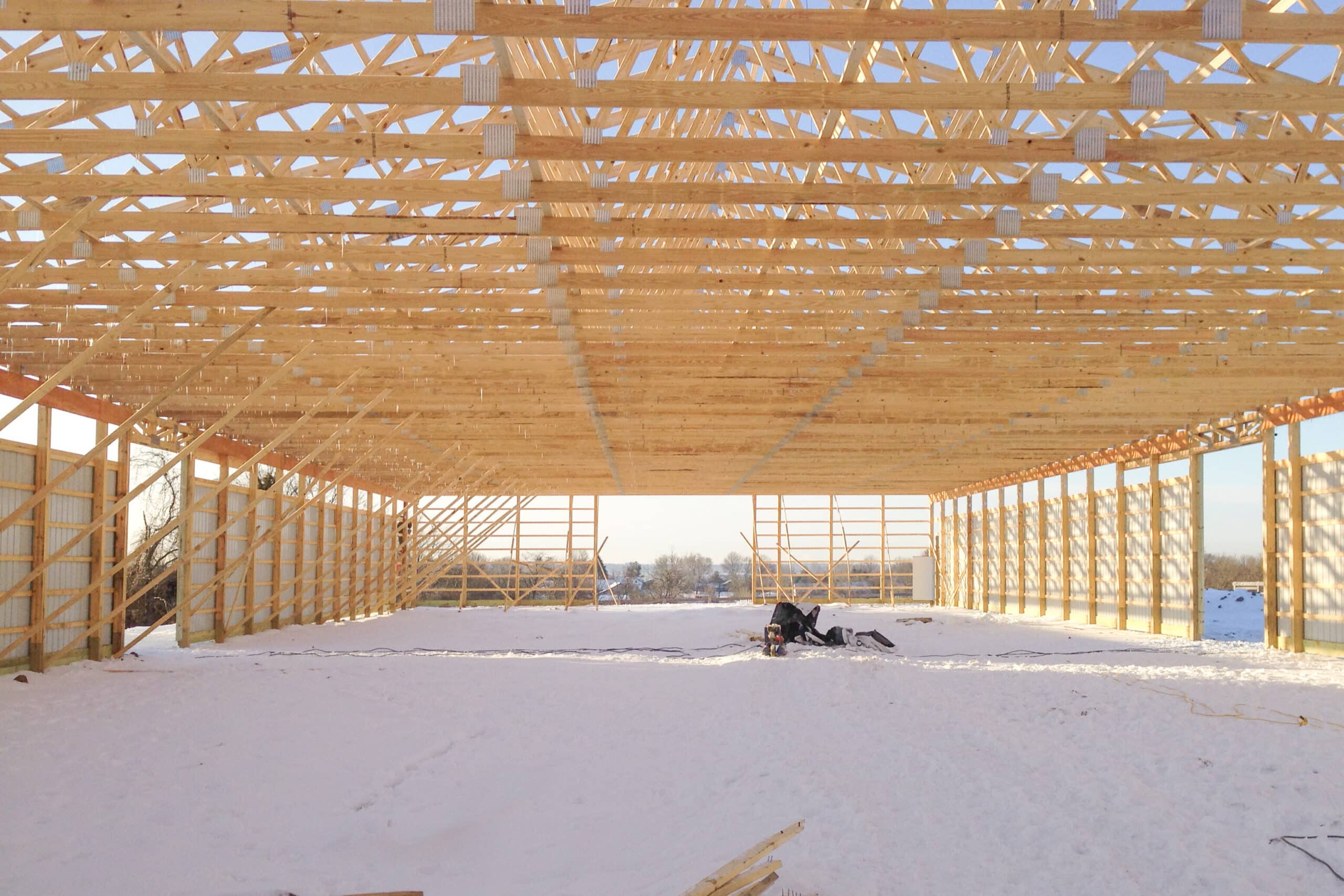 view of wooden roof trusses from inside pole barn frame