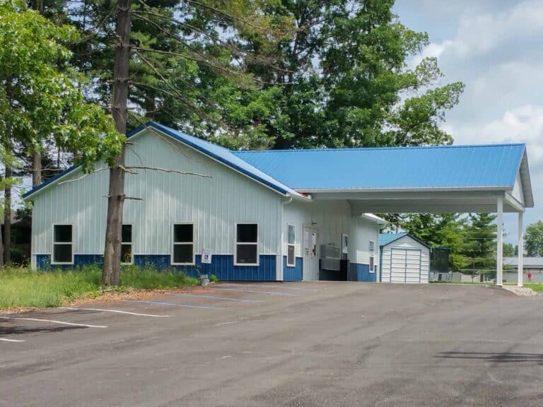 white 50x56 commercial pole barn with blue trim blue metal roof and an overhang