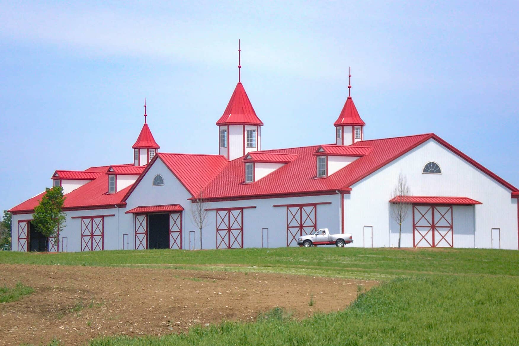 white 60x60 equestrian pole barn with red metal roof