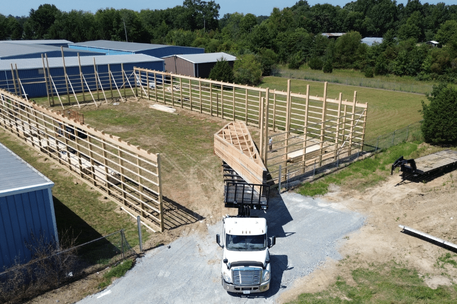 white CMT truck dropping off roof trusses at pole barn garage frame building site