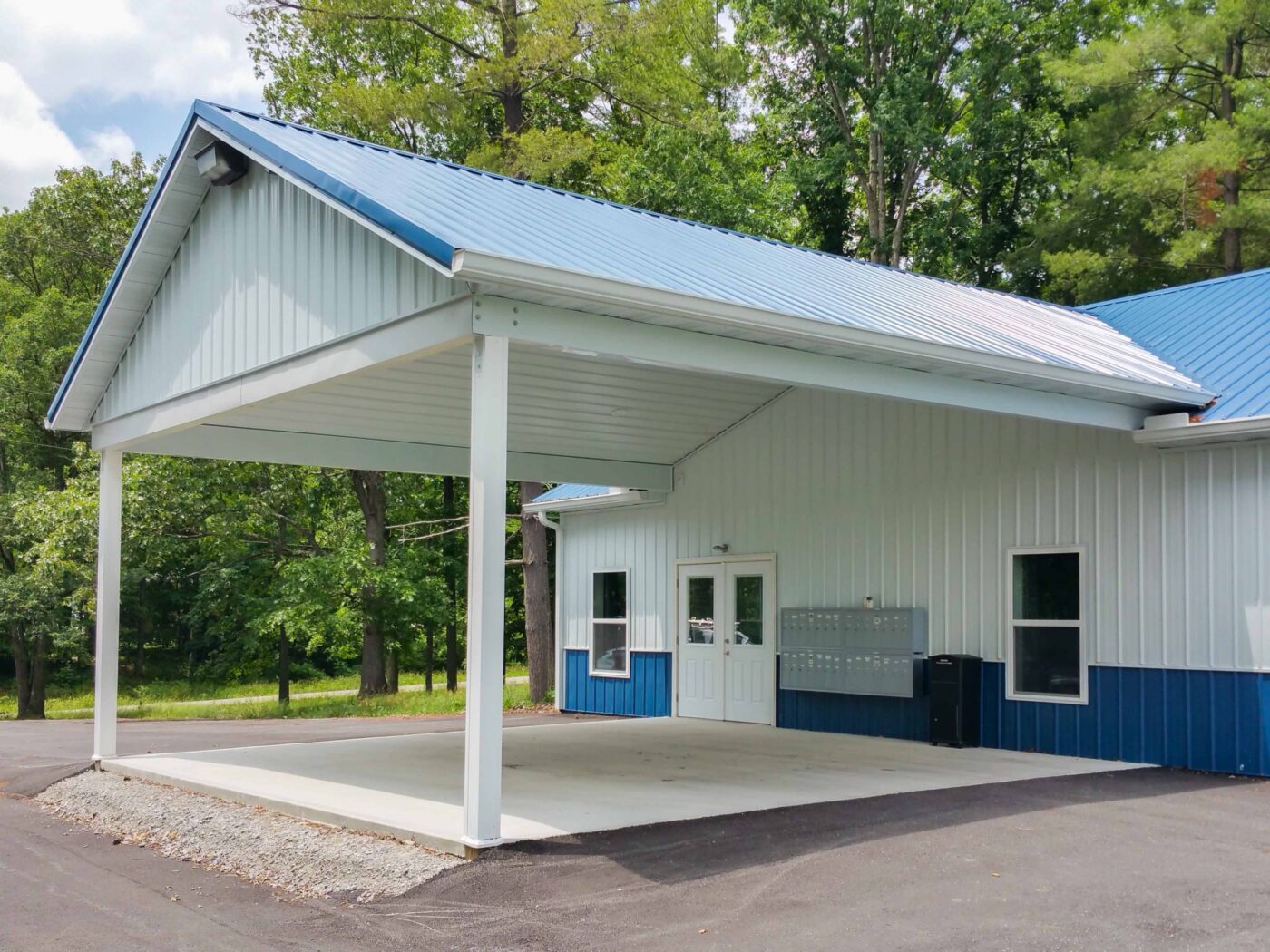 white and blue trimmed 50x100 commercial pole barn kits with blue roof and overhang