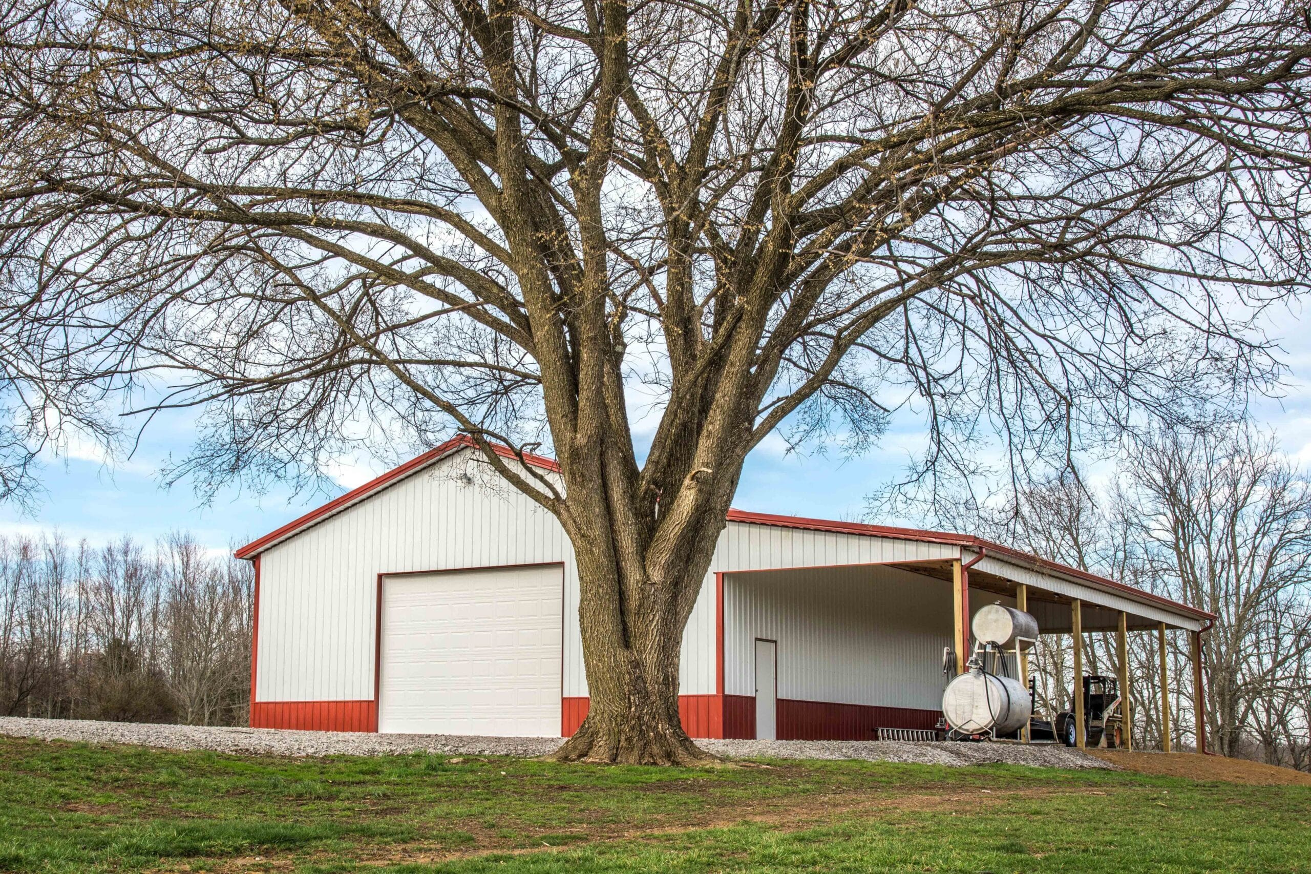 white and red metal pole barn garage with side overhang and one white overhead door