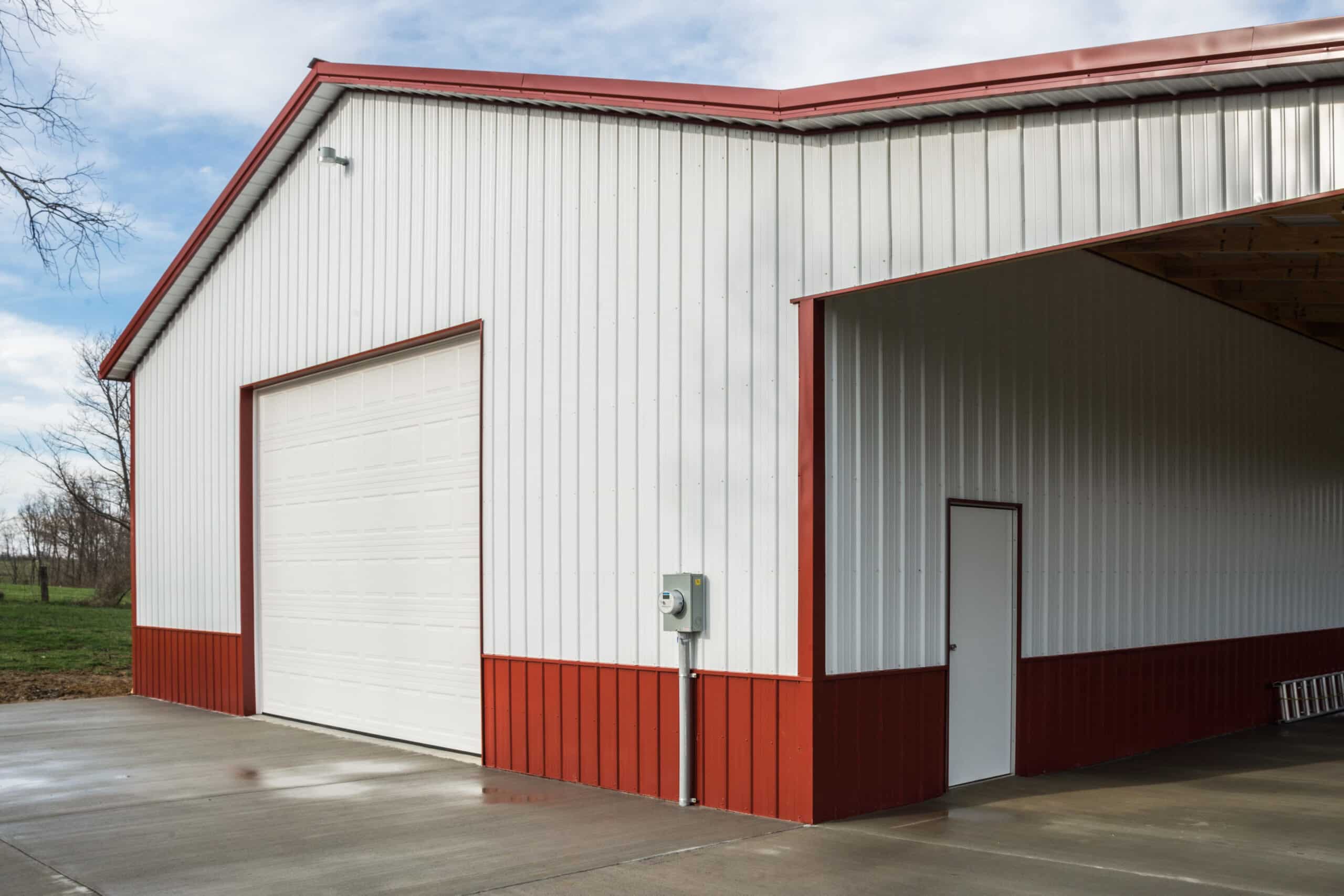 white and red metal siding of pole barn garage with one white overhead door