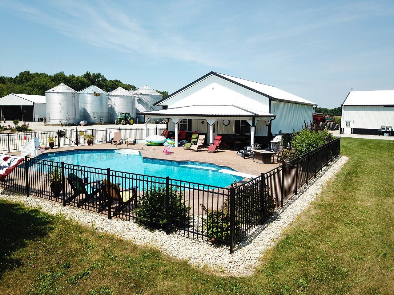 white pole barn with black trim with overhang overlooking a pool