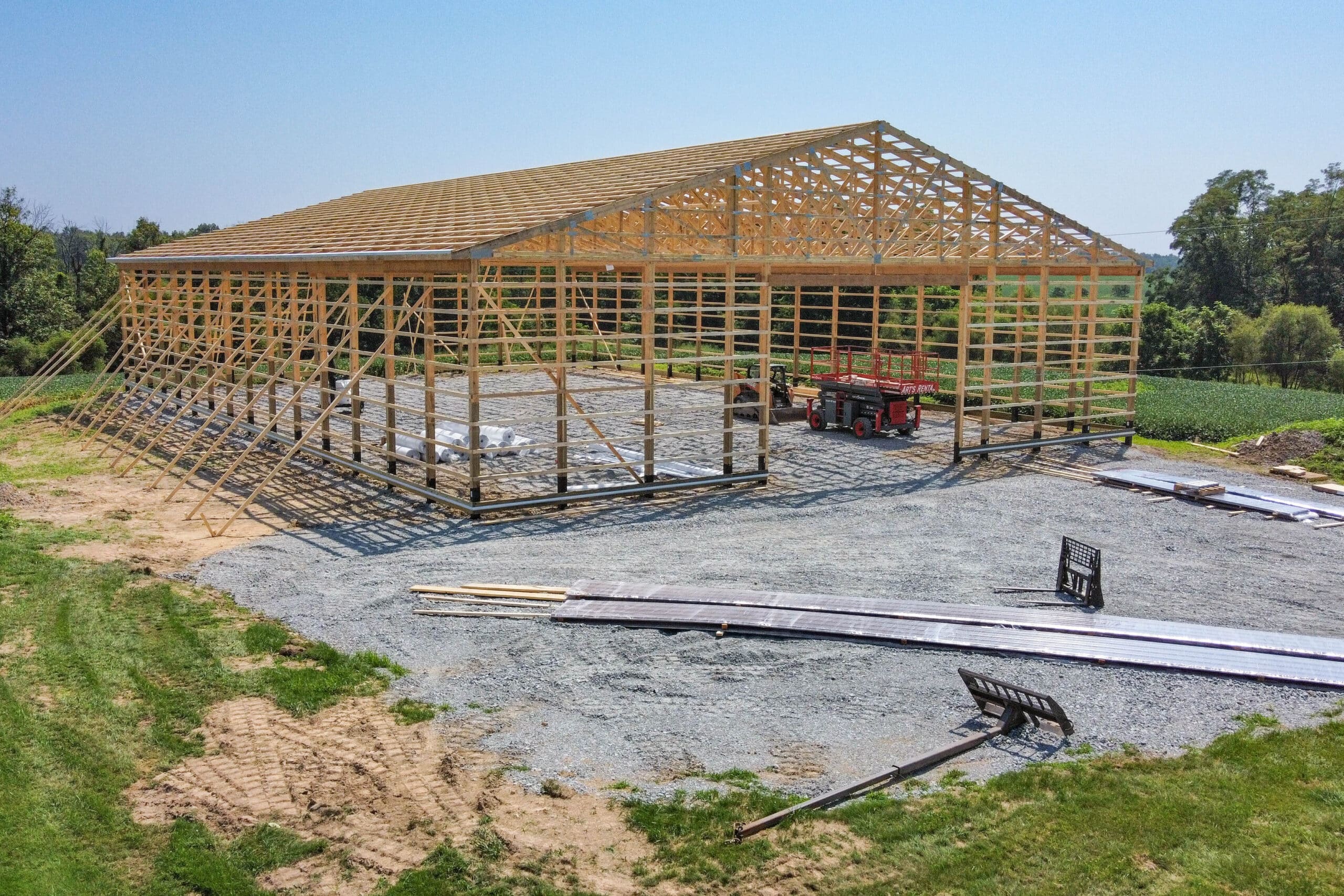 wooden pole barn frame on a gravel pad with lift inside