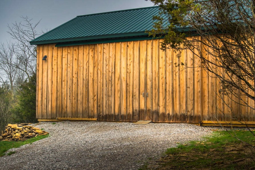 wooden pole barn with green metal roof