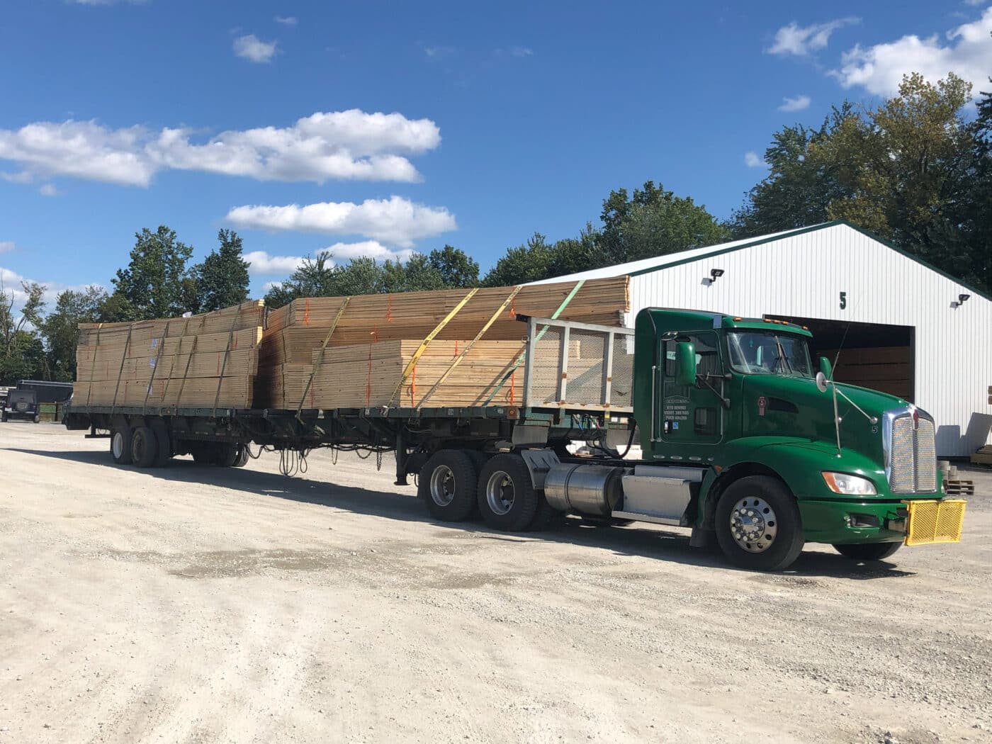 wooden roof trusses strapped to back of green CMT truck