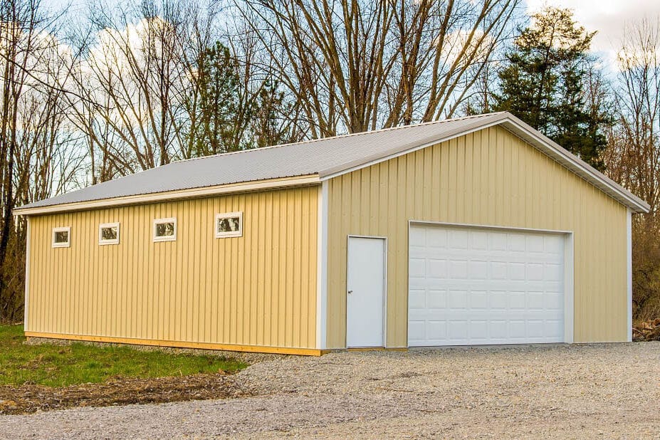 yellow 30x60 pole barn garage with one white double overhead door and a white side door