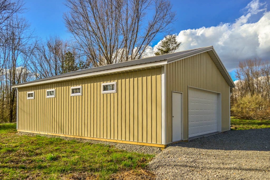 yellow garage pole barn kits in Lancaster OH with white garage door and side door and four windows with white trim on the side