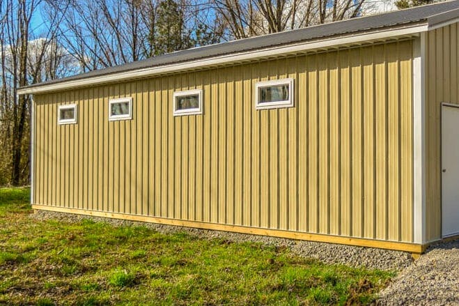 yellow garage pole barn with white overhead door and 4 windows on the side